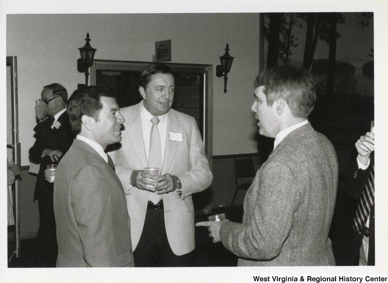 On the left, Representative Nick J. Rahall (D-W.Va.) talks with two unidentified men at an event.
